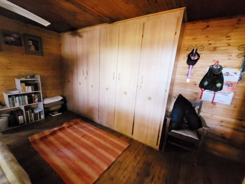 Bedroom featuring extensive built-in cupboards, natural timber wall paneling, and timber ceiling finishes.