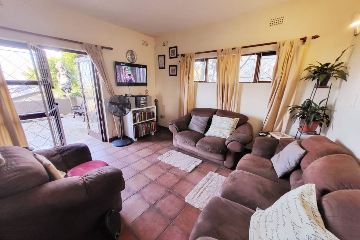 A comfortable living room featuring terracotta floor tiles and direct access to an outdoor patio area through a glass door.