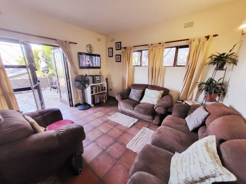 A comfortable living room featuring terracotta floor tiles and direct access to an outdoor patio area through a glass door.