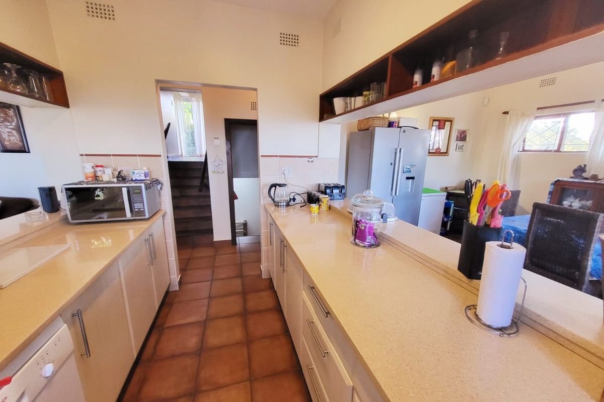 A functional kitchen featuring stone-look countertops, ample cabinetry, and a convenient pass-through window overlooking the adjacent living area.