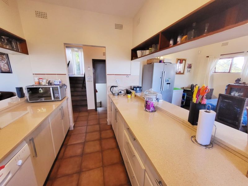A functional kitchen featuring stone-look countertops, ample cabinetry, and a convenient pass-through window overlooking the adjacent living area.