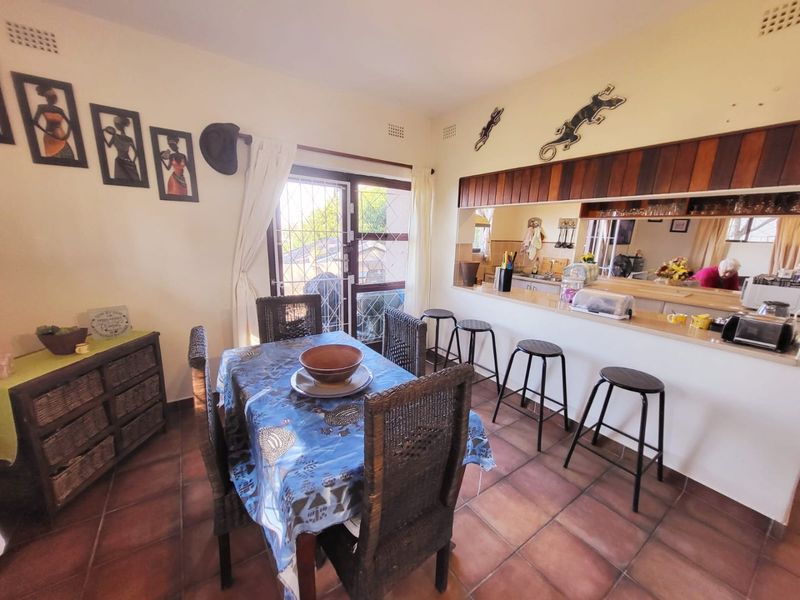 Open plan dining area featuring terracotta floor tiles and a breakfast bar counter overlooking the kitchen space with direct access to the patio.