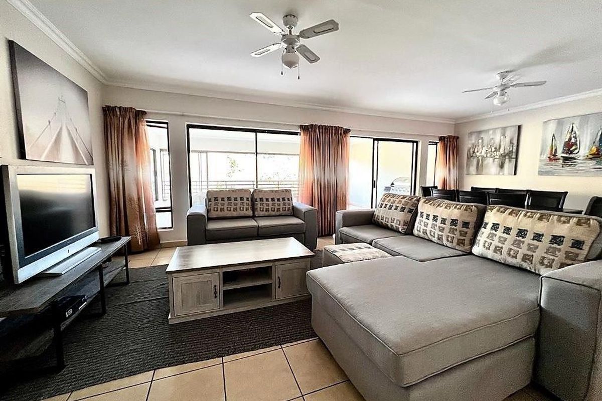 Spacious living room featuring tiled flooring, ceiling fans, and large sliding glass doors providing access to the outdoor area.