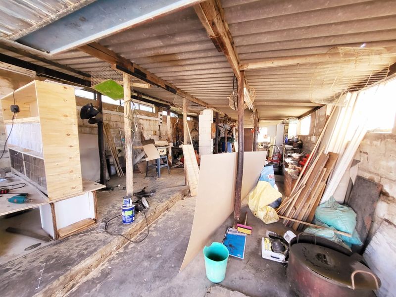 A rustic utility or workshop space featuring exposed timber rafters, concrete flooring, and cinder block walls, suitable for storage or farm-related projects.