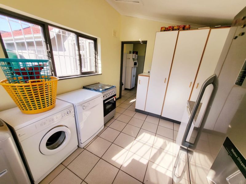 A functional kitchen featuring tiled flooring, built-in cabinetry, and a gas stove, with a secondary prep area visible through the doorway.
