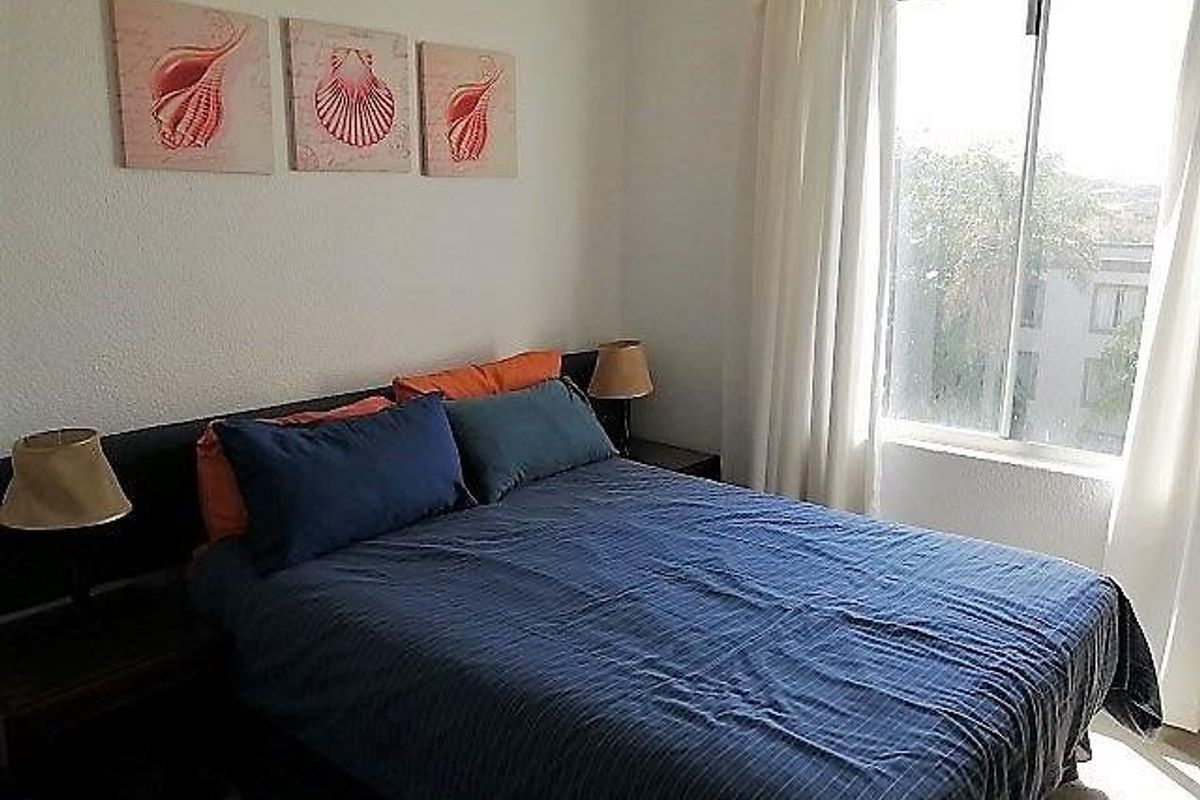 A functional bedroom featuring a large sliding window that provides natural light and views of the surrounding area.