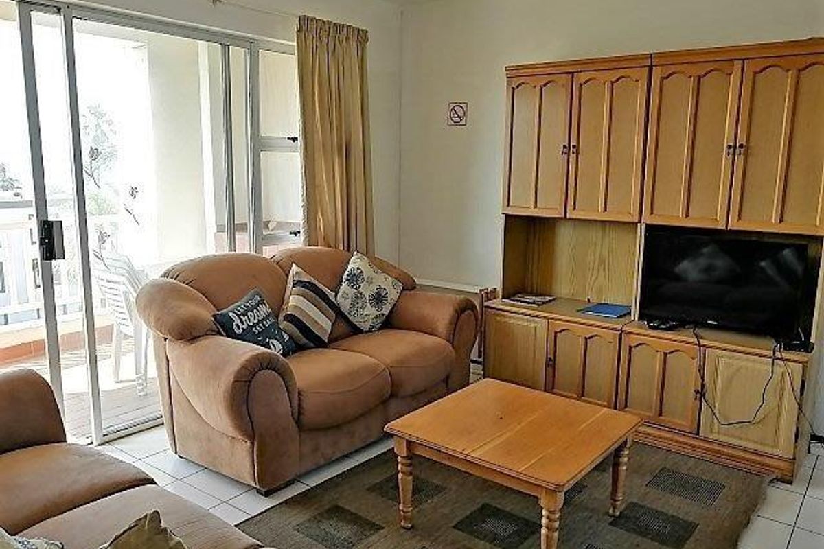 A living room featuring tiled flooring and a large sliding glass door providing access to an outdoor balcony area.