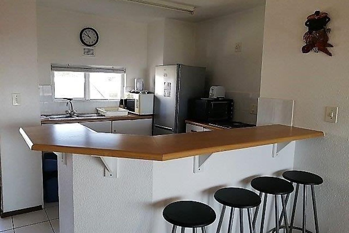 Functional kitchen featuring a breakfast bar, laminate countertops, and tiled flooring, offering a practical layout for daily use.