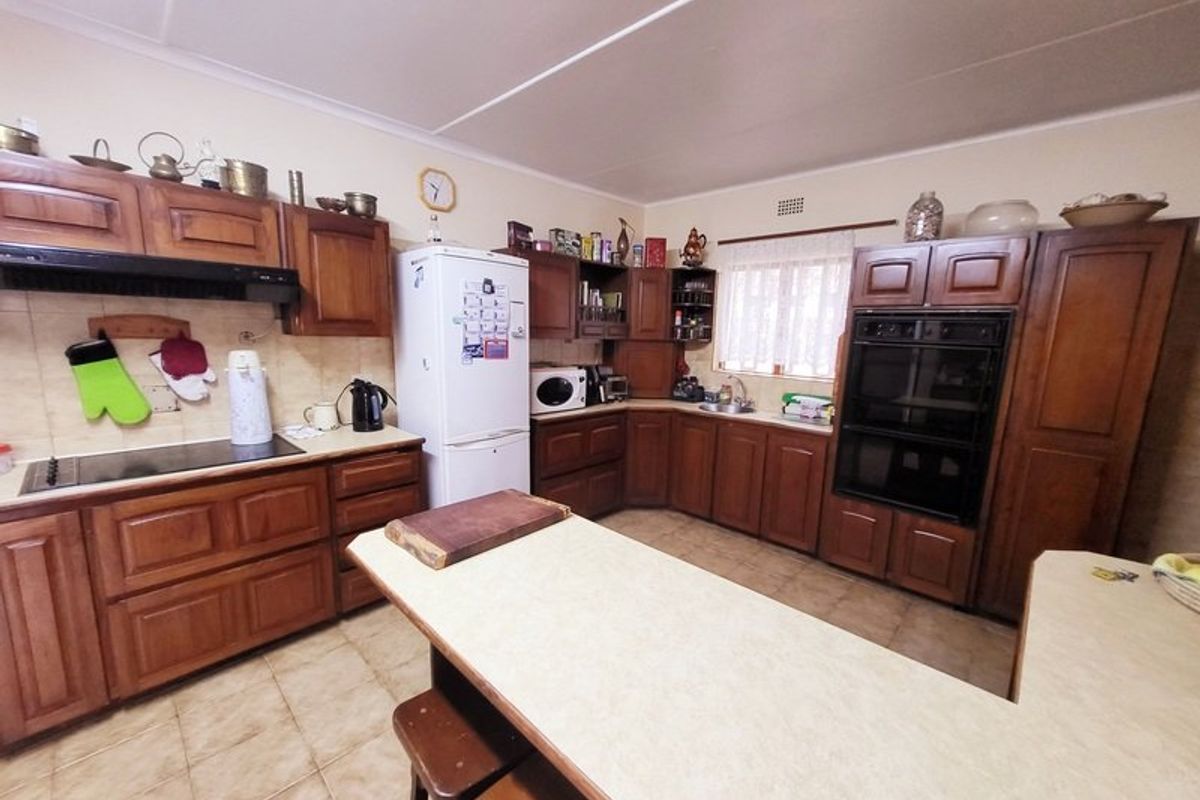 A functional kitchen featuring traditional wooden cabinetry, laminate countertops, a built-in oven, and a ceramic hob with an integrated extractor fan.