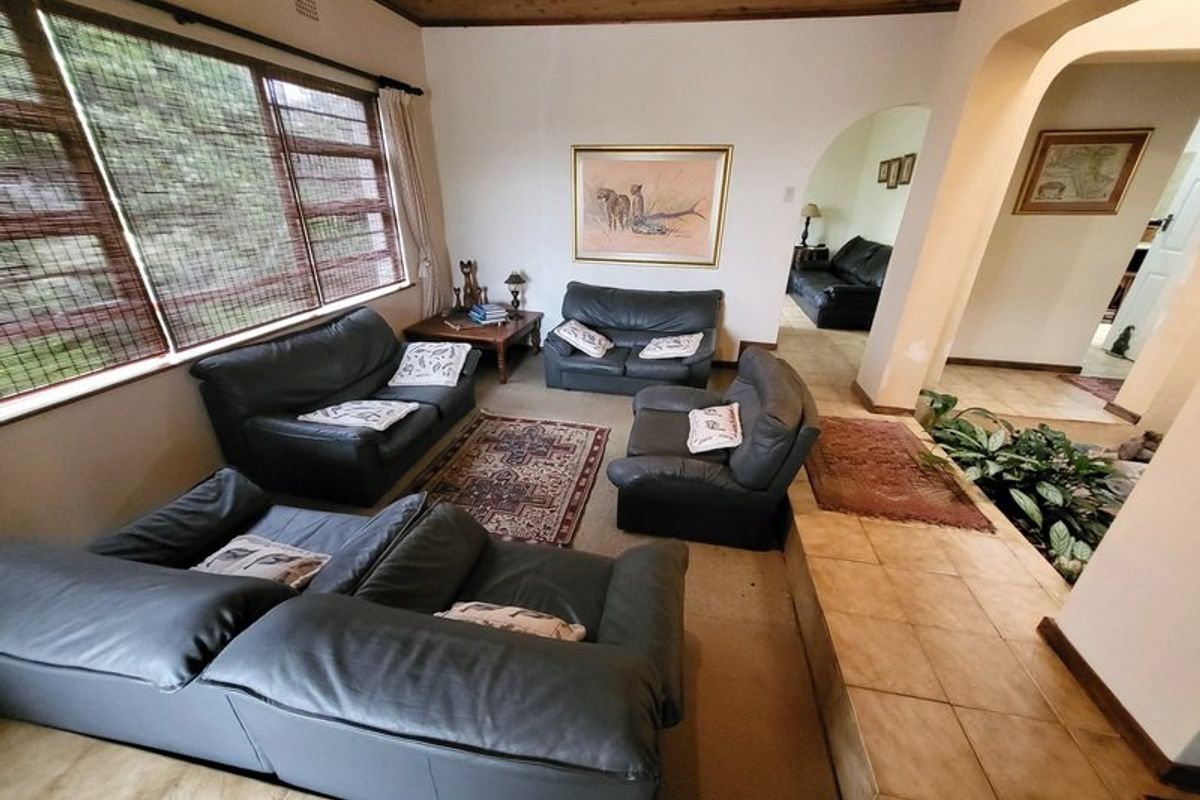 Spacious living room featuring a timber ceiling, tiled flooring, and an open archway leading to adjacent living areas.
