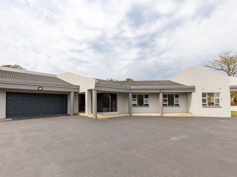 Front elevation of a modern single-story house featuring a spacious asphalt driveway, double garage, and neutral exterior finishes.