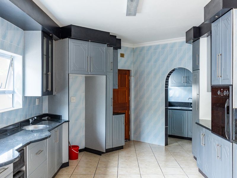 Spacious kitchen featuring built-in cabinetry, granite countertops, integrated oven, and a separate scullery area accessed through a classic archway.