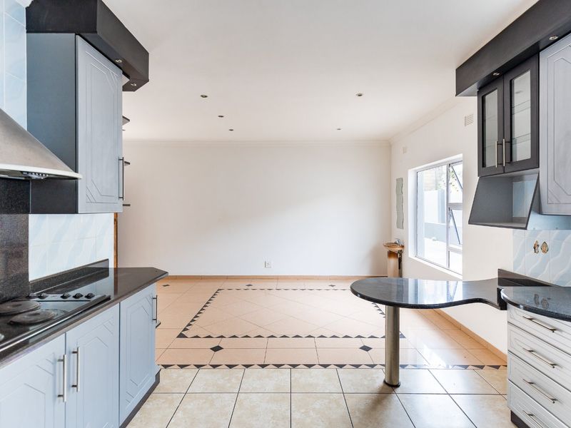 Open plan kitchen and living area featuring built-in cabinetry, granite countertops, and tiled flooring throughout.