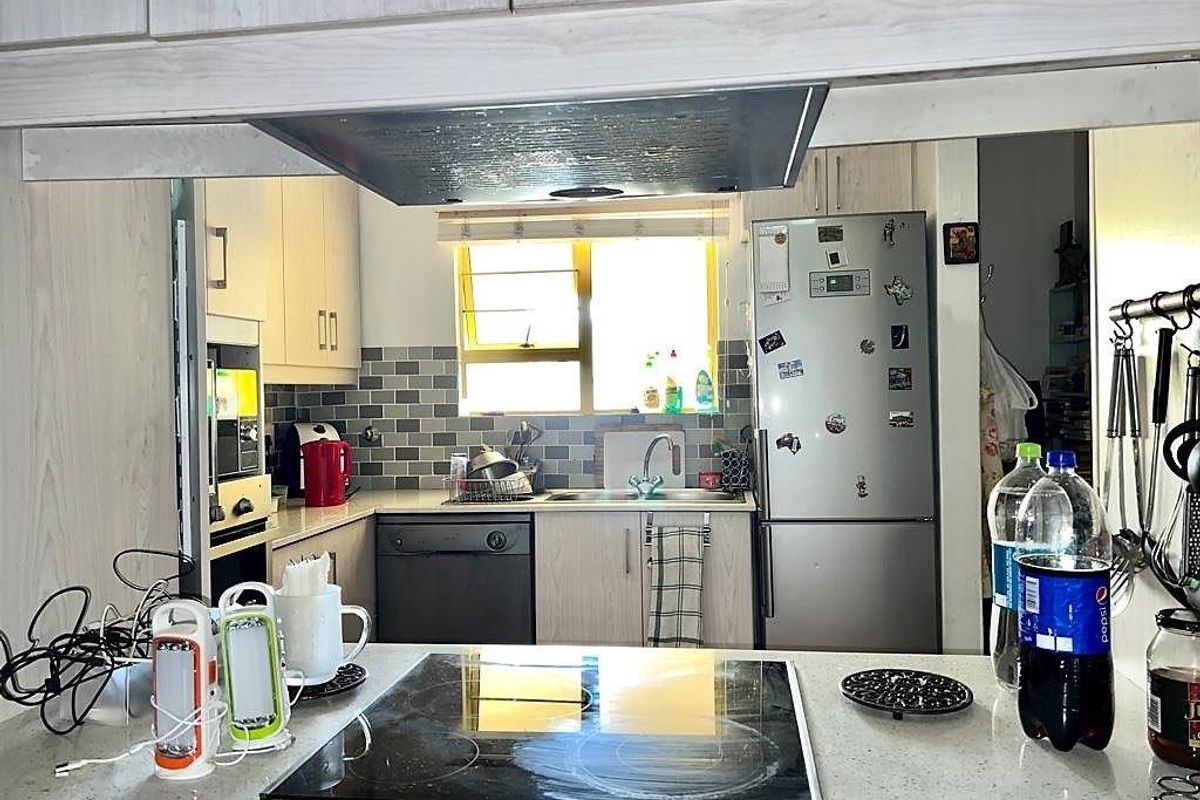 Functional kitchen featuring built-in cabinetry, stone countertops, an electric hob, extractor fan, and a subway tile backsplash.
