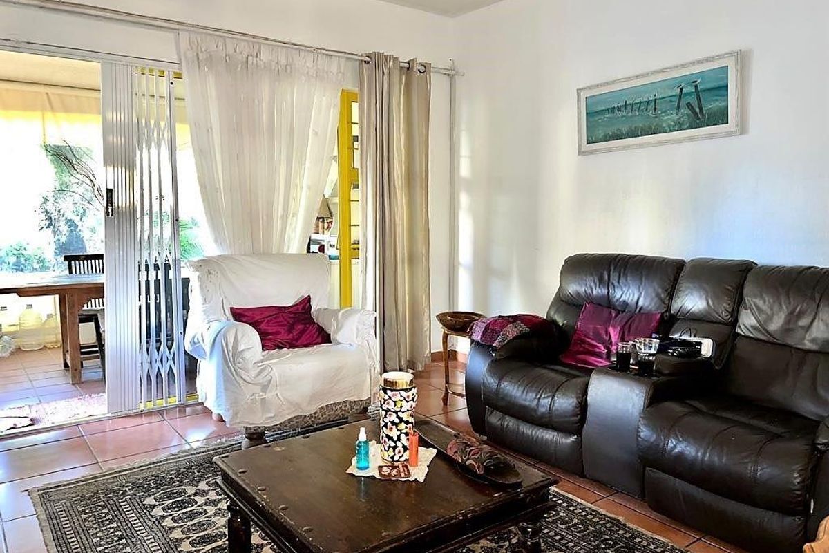 Living room featuring tiled flooring and a sliding glass door with security gate providing access to an outdoor patio area.