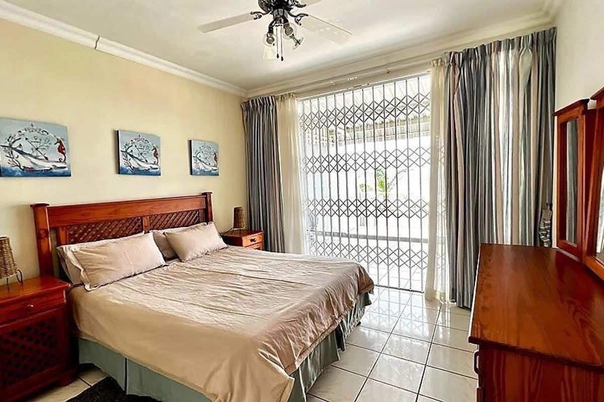 A bedroom featuring tiled flooring, a ceiling fan, and a sliding glass door with a security gate leading to an outdoor area.