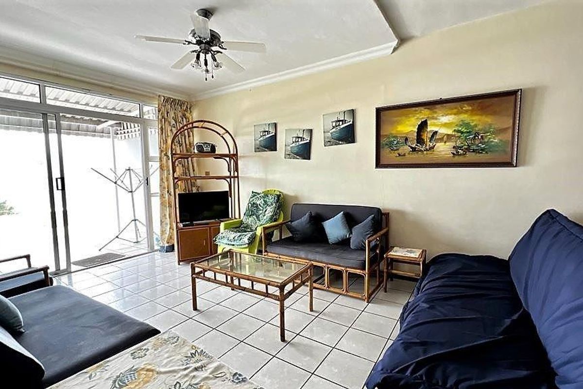 A living room featuring tiled flooring, a ceiling fan, and large sliding glass doors providing access to an outdoor area.