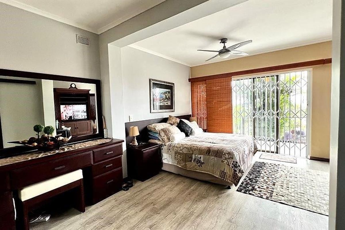 Spacious bedroom featuring laminate flooring, a ceiling fan, and sliding glass doors providing direct access to the outdoor area.