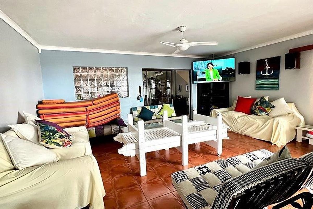 Spacious living room featuring terracotta floor tiles, a ceiling fan, and a unique glass block feature window, offering a comfortable and functional living space.