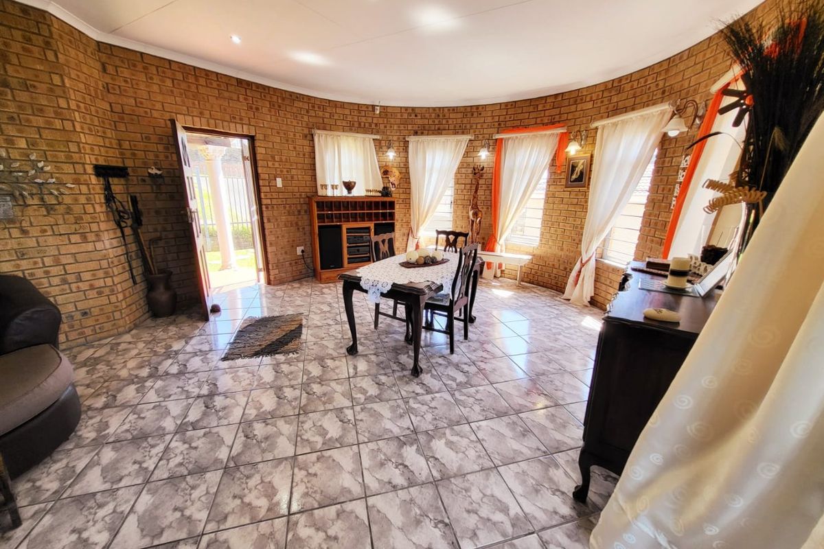 Spacious living area featuring distinctive curved exposed brick walls, tiled flooring, and abundant natural light through multiple windows.