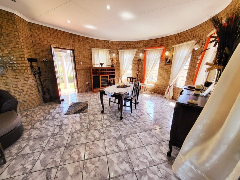 Spacious living area featuring distinctive curved exposed brick walls, tiled flooring, and abundant natural light through multiple windows.