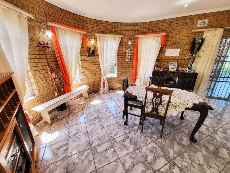 A circular dining room featuring exposed brick walls, tiled flooring, and multiple windows providing natural light.