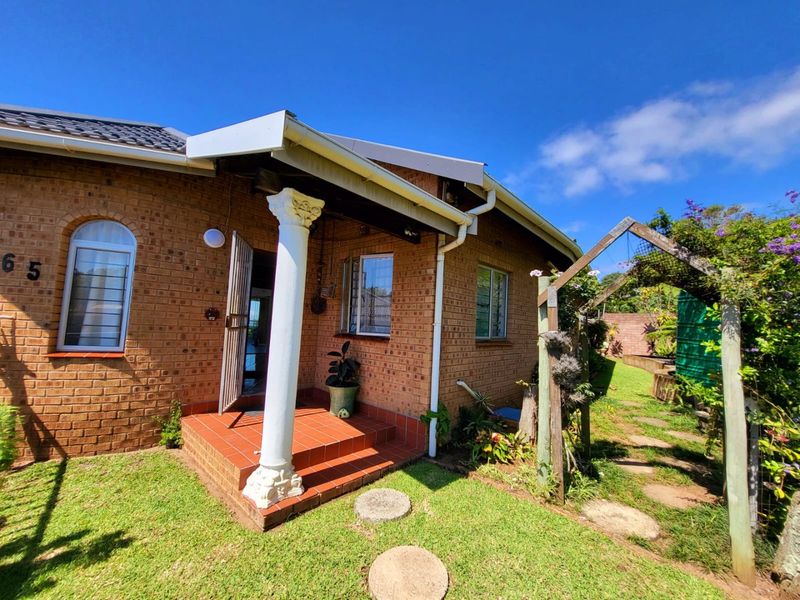 Front elevation of a face brick house featuring an arched window, a decorative column at the entrance porch, and a timber garden arch.