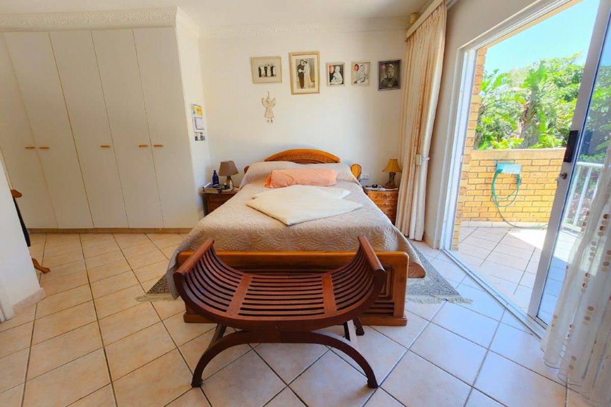 Spacious bedroom featuring tiled flooring, built-in cupboards, and direct access to an outdoor patio through a sliding glass door.