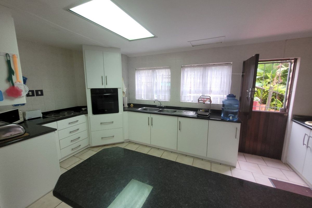 A functional kitchen featuring white cabinetry, dark granite countertops, a built-in oven, and a double sink with direct access to the exterior.