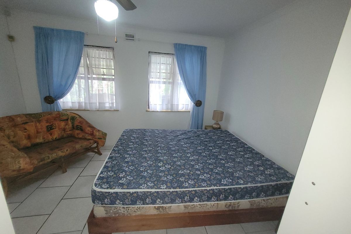 A bedroom featuring tiled flooring and a ceiling fan, with two windows providing natural light.