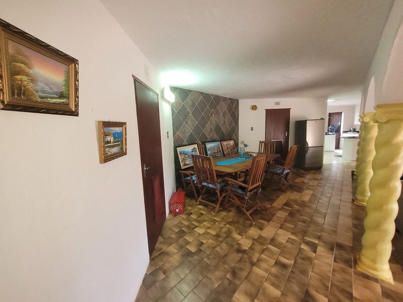 Open plan dining area featuring tiled flooring, decorative columns, and a tiled feature wall, leading through to the kitchen area.