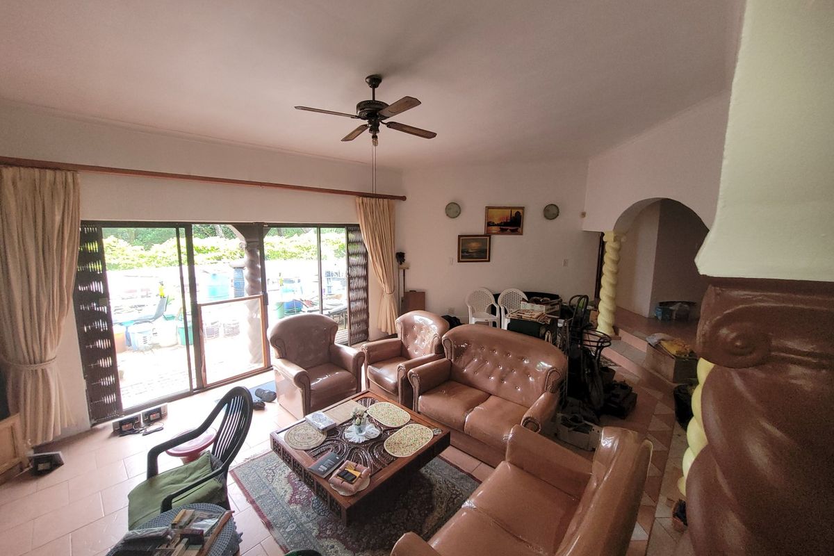 Spacious living room featuring tiled flooring, a ceiling fan, and large sliding glass doors that provide access to the outdoor area.