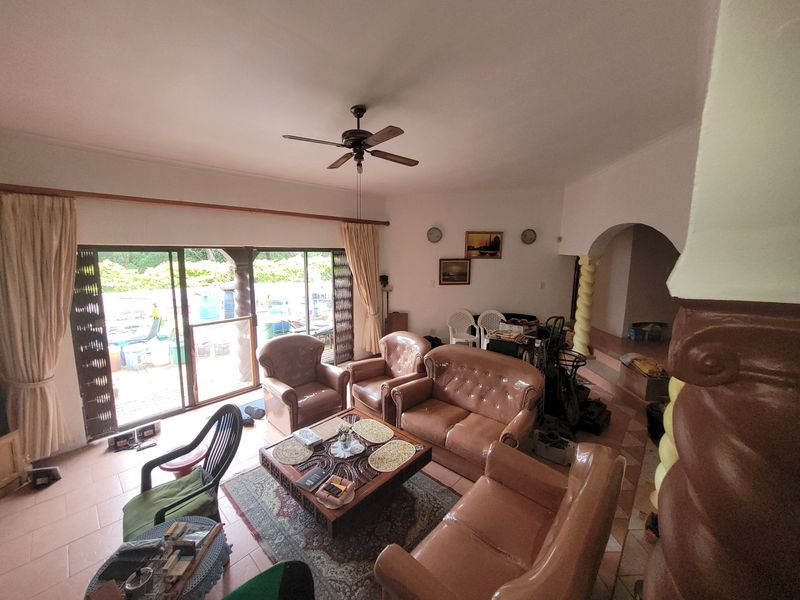 Spacious living room featuring tiled flooring, a ceiling fan, and large sliding glass doors that provide access to the outdoor area.