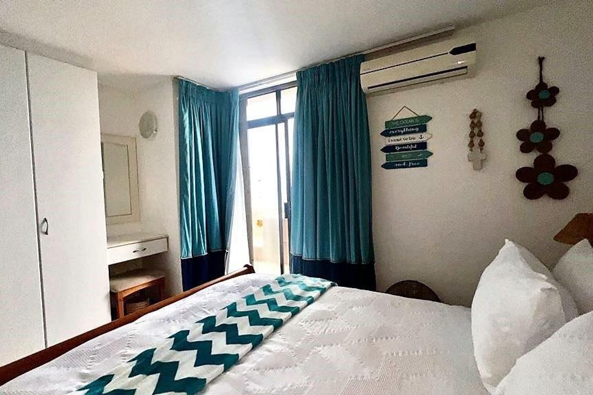 A bedroom featuring built-in cupboards, a vanity area, and a wall-mounted air conditioning unit, with direct access to an outdoor balcony.