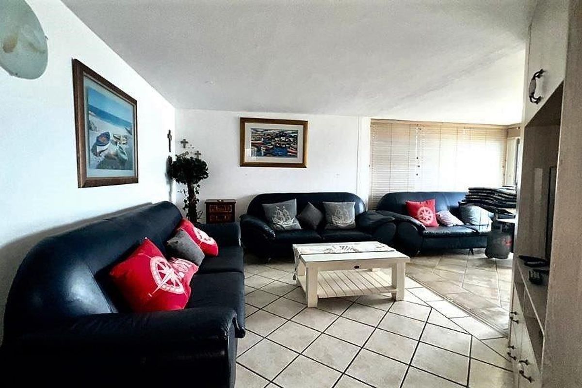 A spacious living area featuring tiled flooring and large windows with blinds, providing ample natural light.