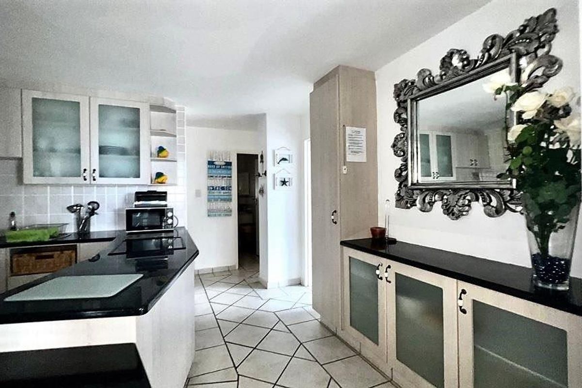 A functional kitchen featuring dark granite countertops, light-toned cabinetry with frosted glass inserts, and tiled flooring throughout the space.