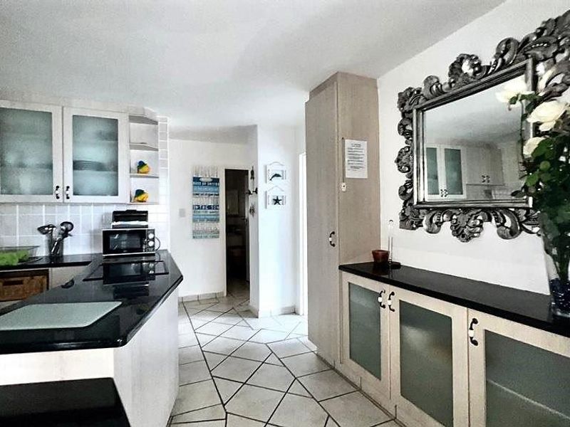A functional kitchen featuring dark granite countertops, light-toned cabinetry with frosted glass inserts, and tiled flooring throughout the space.