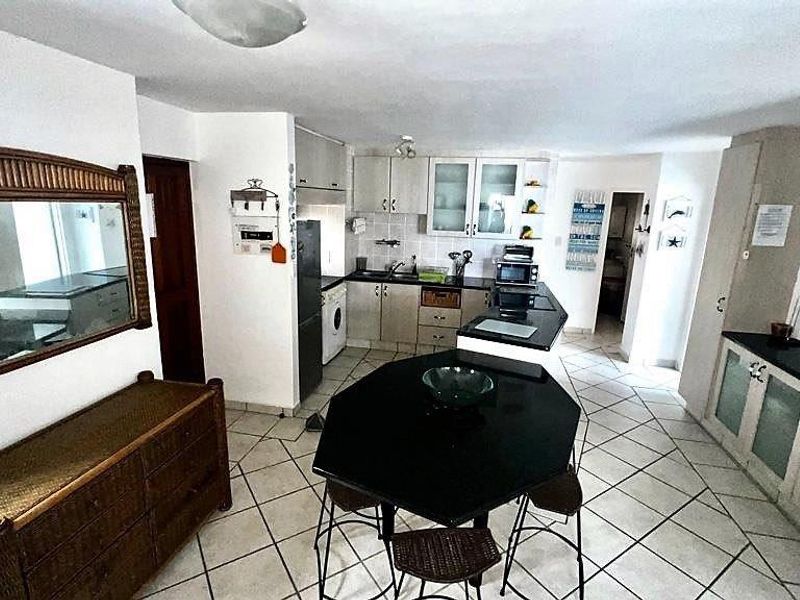 Open plan kitchen featuring dark countertops, built-in cabinetry, and tiled flooring, seamlessly flowing into the adjacent living area.