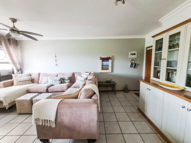 A spacious living room featuring tiled flooring, a ceiling fan, and built-in cabinetry, offering a comfortable and functional living space.