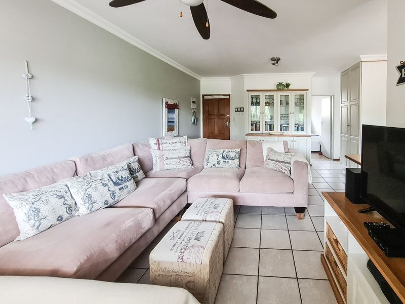 A comfortable living room featuring tiled flooring, a ceiling fan, and built-in cabinetry providing ample storage and display space.