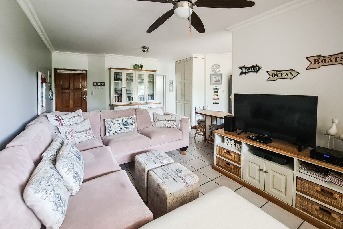 A comfortable living room featuring tiled flooring, a ceiling fan, and built-in cabinetry, offering a functional and well-maintained living space.