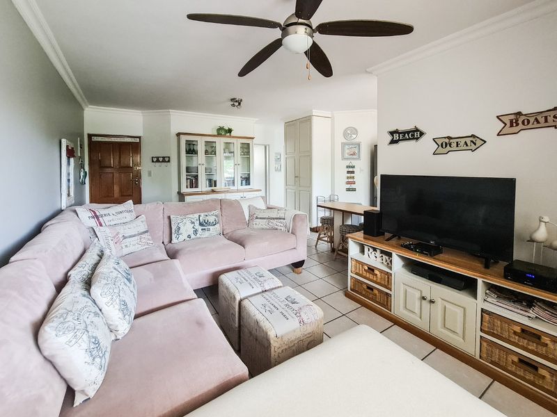 A comfortable living room featuring tiled flooring, a ceiling fan, and built-in cabinetry, offering a functional and well-maintained living space.