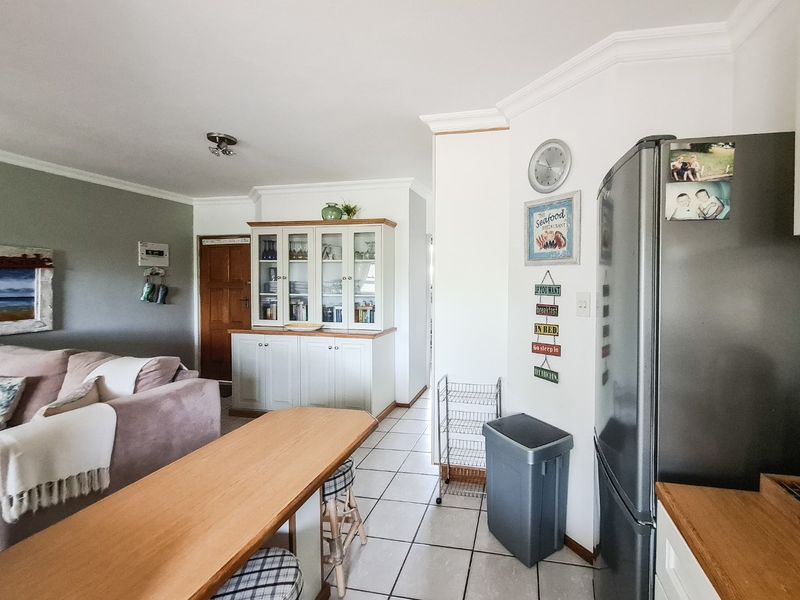 Open plan living and kitchen area featuring tiled flooring, built-in cabinetry, and crown molding, creating a functional and connected living space.
