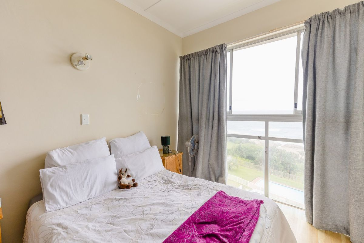 A bedroom featuring a large sliding window with natural light and views, complemented by a wall-mounted light fixture.