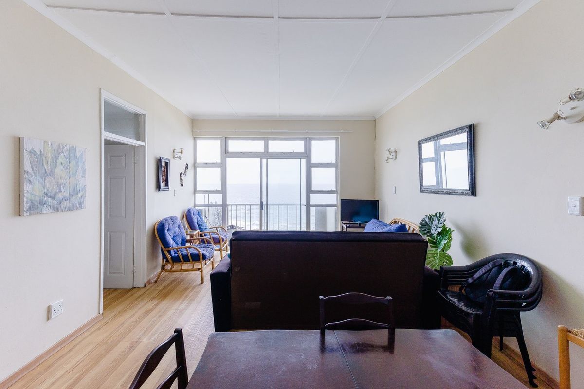 A living room featuring laminate flooring, ceiling paneling, and a large sliding glass door providing natural light and access to the balcony.