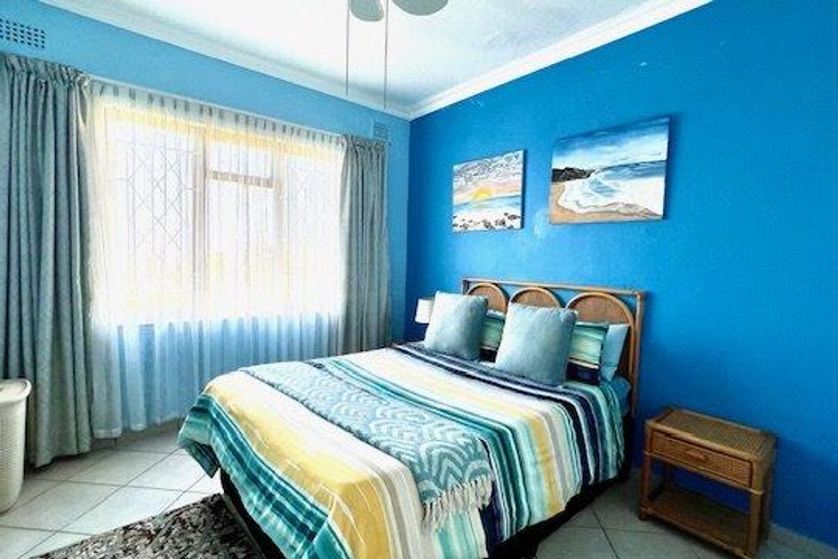 A bedroom featuring tiled flooring, a ceiling fan, and a window fitted with security bars.