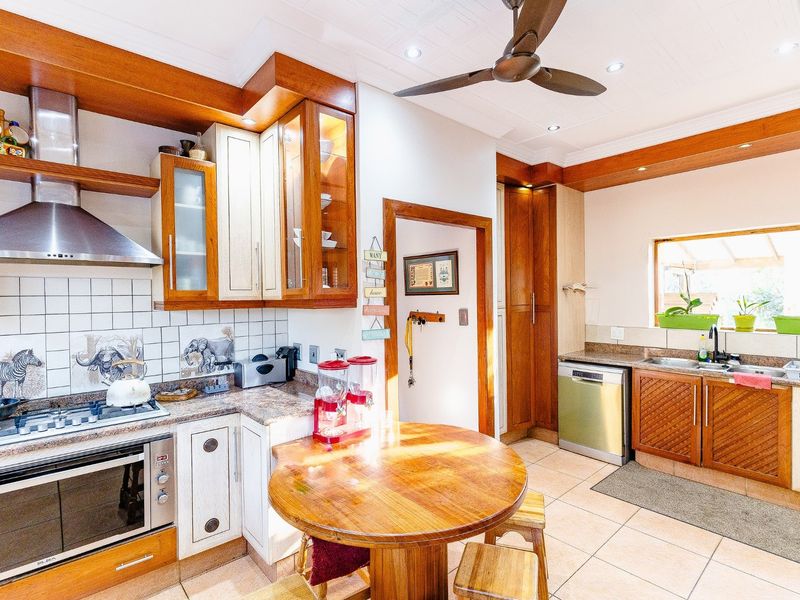 A well-maintained kitchen featuring wooden cabinetry, granite countertops, a gas hob, built-in oven, and a central breakfast nook area.