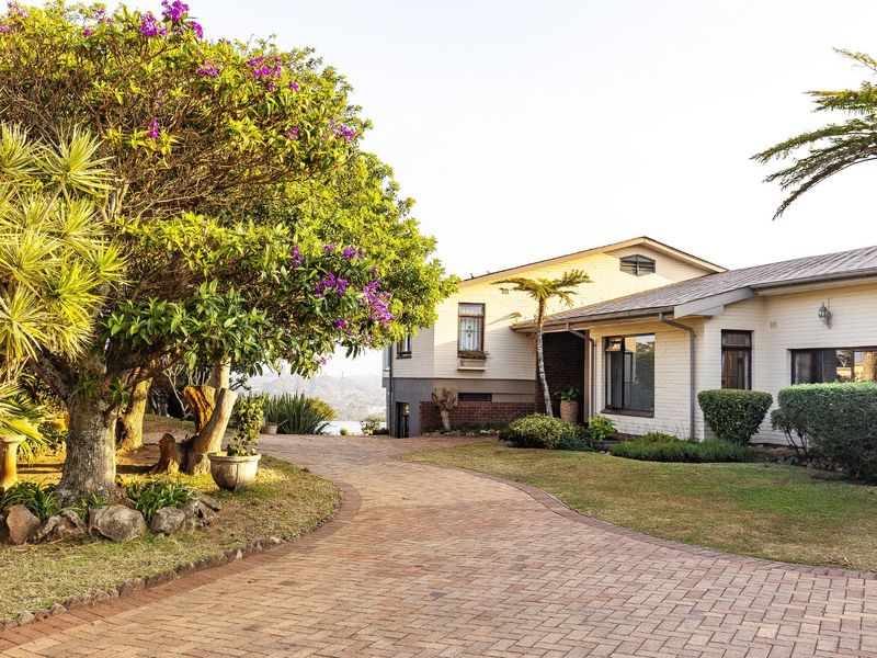 A well-maintained single-story residence featuring a painted brick exterior, a paved driveway, and established garden landscaping.