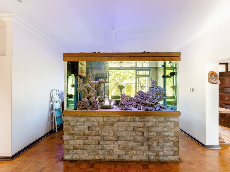 Spacious living area featuring a prominent stone-clad built-in aquarium and classic parquet flooring, offering a unique focal point for the home.