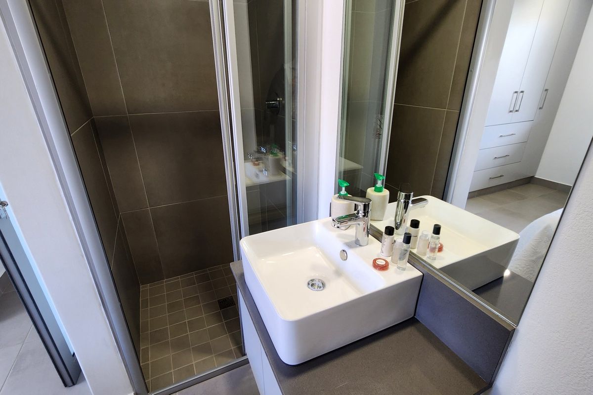 Modern bathroom featuring a vessel sink with chrome faucet, a tiled shower enclosure, and a large wall mirror.